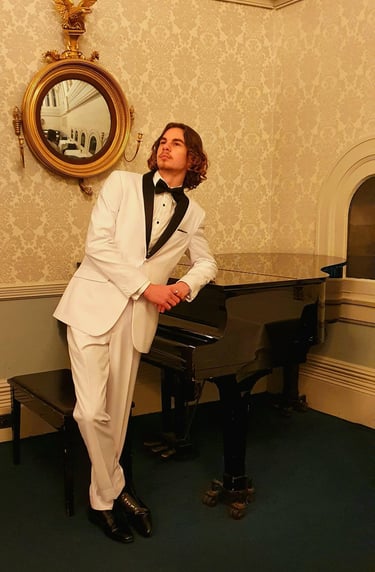 a man in a white suit and a piano