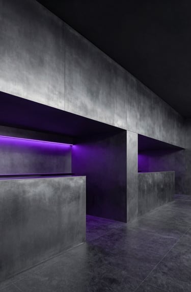 Wide architectural shot of a minimalist, modern club interior in a Spanish / Latin American capital. Sleek surfaces in steel grey and rich deep black, with subtle accent lighting in vibrant electric violet. Empty space, sophisticated vibe.