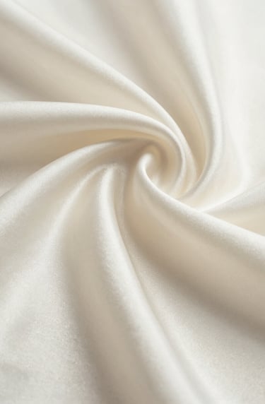 Macro photography of high-quality, rippled silk fabric in a soft off-white color. The shot focuses on the elegant texture and the way light reflects off the subtle sheen. Inspired by high-end North American / Western European editorial design.