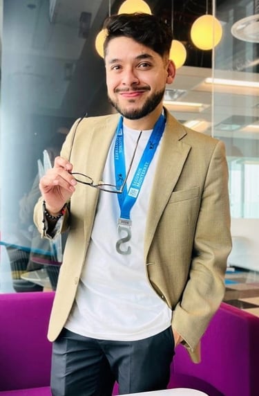 Alán Ángeles asesor con chaqueta color beige, luciendo una medalla de premio y sosteniendo sus gafas