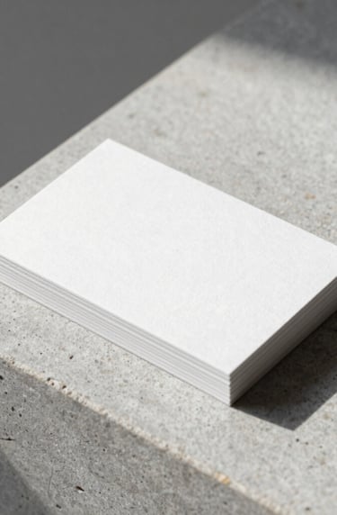 A minimalist brand identity mockup featuring a sleek business card on a light gray stone texture. The design is purely typographic and sophisticated, with sharp edges and a clean layout, illuminated by soft morning sunlight in a professional studio setting.