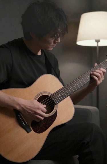 A medium shot of a person playing a guitar in a dimly lit room. The composition is off-center and artistic. Shadows are dark slate grey, while a soft off-white lamp glow illuminates the warm taupe wood of the guitar.