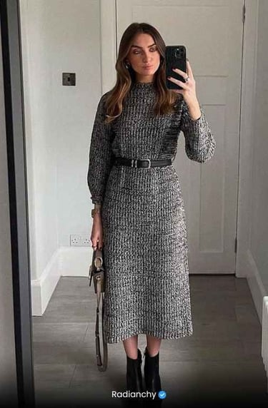 a woman in a gray dress and boots is taking a selfie