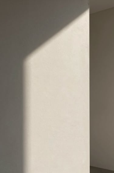 Abstract photography of light hitting a textured wall in a modern building, soft off-white and medium grey tones, elegant and minimalist composition.