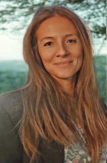 Smiling woman with long blonde hair outdoors in a natural green background.