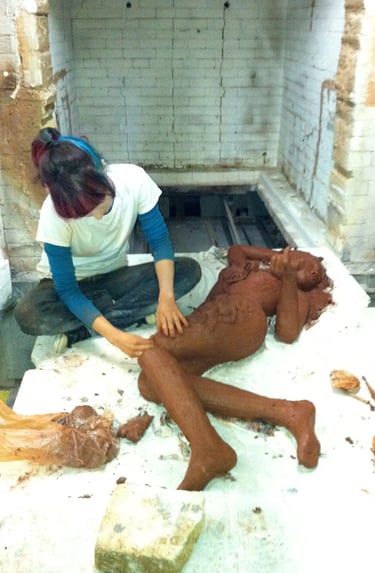 Girl sculpting a ceramic girl in a huge kiln