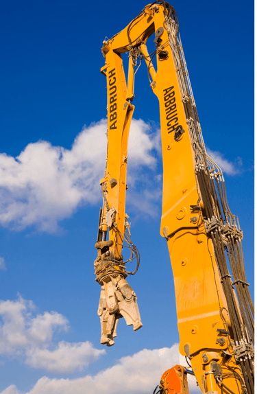 Long-reach demolition excavator with a hydraulic concrete cutter attachment against a blue sky.