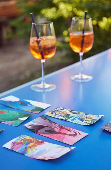 Aperol Spritz Glasses on a blue table with artwork.
