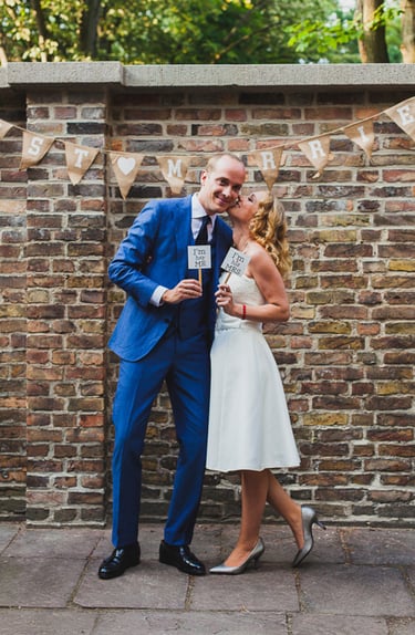 Frischvermählte vor einer Backsteinmauer.