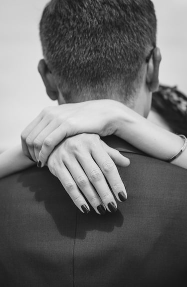 Die Hände der Braut auf den Schultern des Bräutigams.