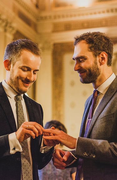 Homosexuelle Bräutigame tauschen Ringe aus.