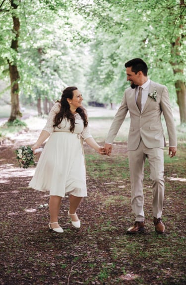 Lachendes Brautpaar auf einem Parkweg.