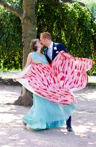 Braut und Bräutigam halten ein ausgeschnittenes Herz in den Händen.