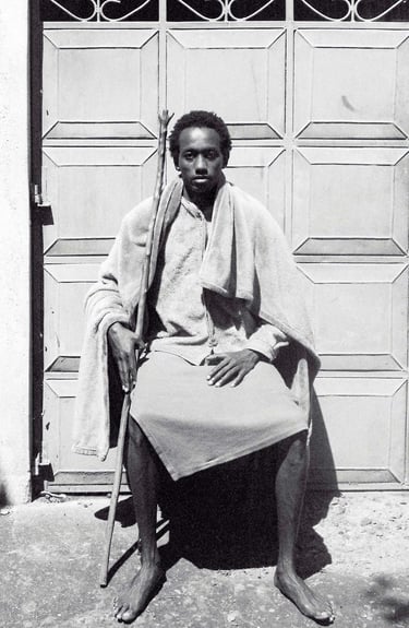 Manjahi Njoroge, a man sitting on a chair in front of a door