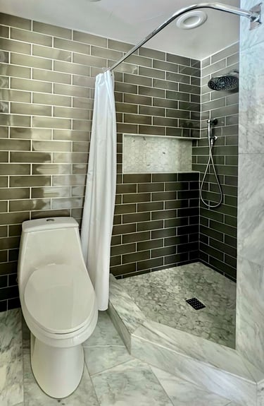 A bathroom with marble floor tile, and full height grey subway wall tile.