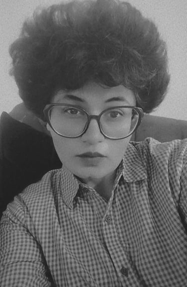 Eeta Noire, with a curly hair and glasses