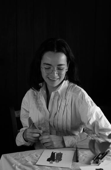 Fotografia en blanco y negro de Ana de Studio Anneta pintando un retrato y sonriendo