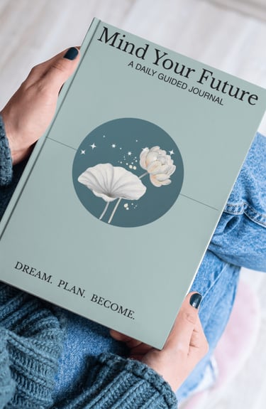 A person holds the Mind Your Future daily guided journal featuring a lotus flower design.