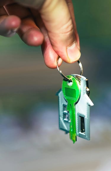 Une main tenant un trousseau de clés avec un porte-clés en forme de maison pour l'achat d'une propri