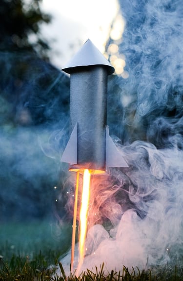 a rocket made of craft supplies is launching in a yard