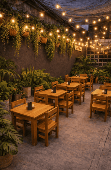 Acogedor restaurante al aire libre con mesas de madera, luces colgantes y exuberantes plantas verdes