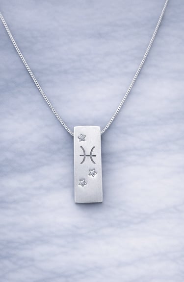 Handmade 999 silver Pisces zodiac necklace with a vertical bar pendant on a marble surface.