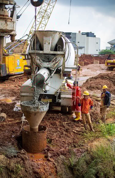 mesin pengaduk semen sedang dijalankan oleh seorang pekerja konstruksi. jasa photography jakarta