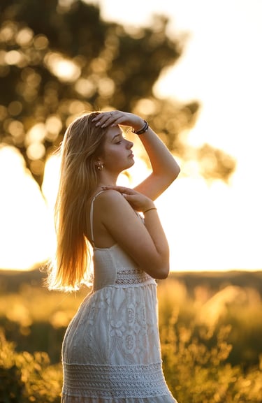 une jeune femme dans un champ au coucher du soleil