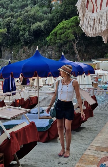 Mary Tornariti on sandy beach with blue umbrellas at Paraggi Bay near Portofino.