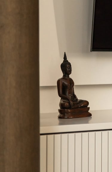 Zbliżenie na dekoracje: drewniana figurka Buddy w minimalistycznym wnętrzu.
