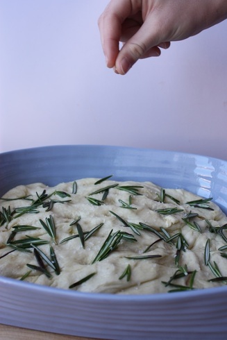 salt being added to the uncooked dough of rosemary focaccia bread