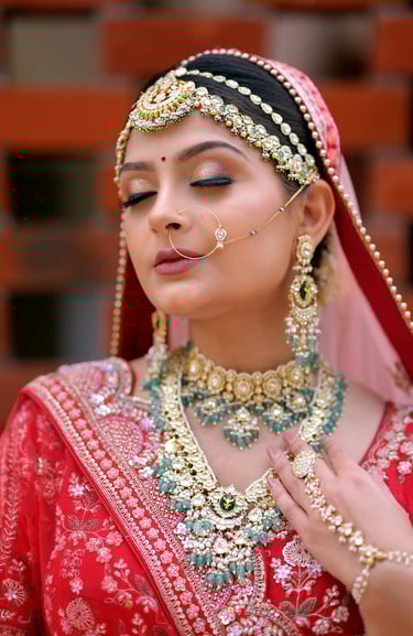 Traditional Indian bride in red lehenga with heavy jewelry, maang tikka, and flawless bridal makeup.
