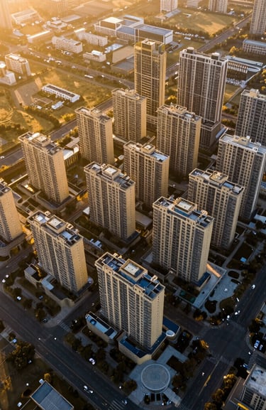High-contrast architectural drone photography of a master-planned commercial land plot, golden hour low-sun angle, deep shadows, rich gold tones