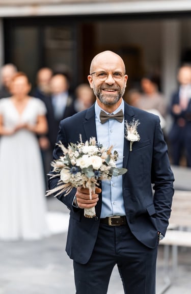 Un homme en costume avec un bouquet de fleurs à la main