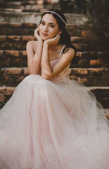 mujer adolescente en un vestido rosa sentada en las escaleras celebrando sus XV años