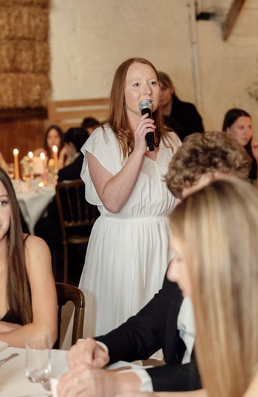 woman in white dress talking to the microphone during an event