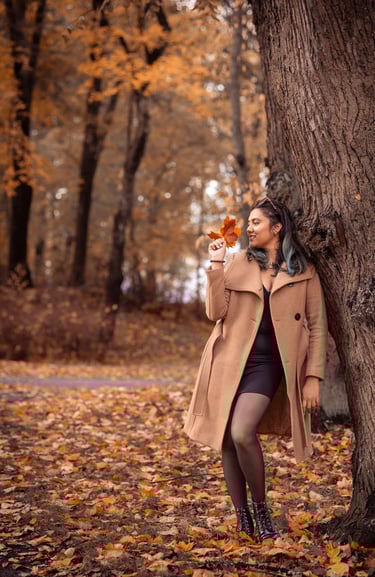 a woman in a coat and boots standing in front of a tree
