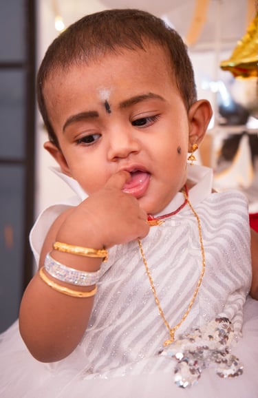 a young child with a white dress and gold jewelry