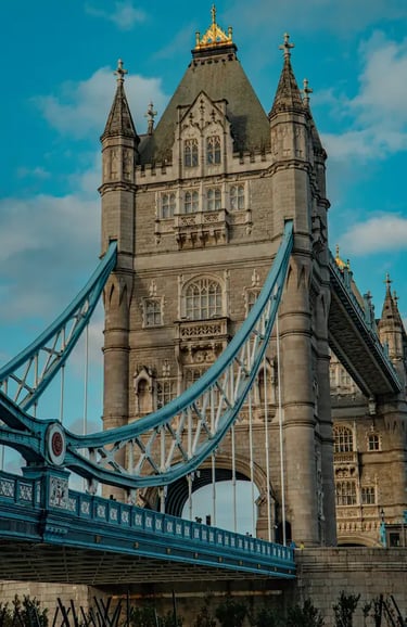 Close-up of the historic Tower Bridge in London featuring blue suspension cables and gothic stone architecture.