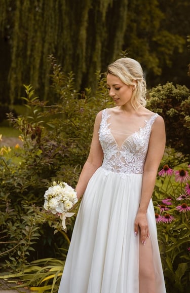 a woman in a white dress standing in front of a flower garden