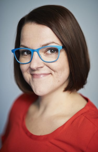 Foto der Geschäftsführerin. Rotes Oberteil und blaue Brille