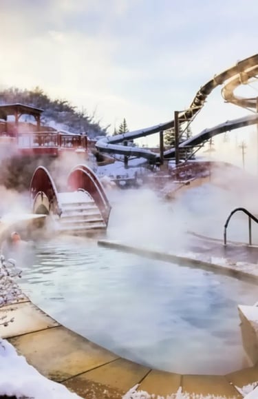 Steaming outdoor thermal pool with a wooden bridge and a large water slide in the background during 