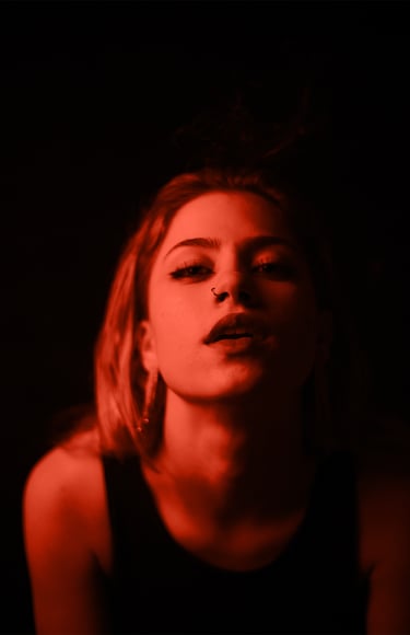 Fotografía de actriz en fondo oscuro con detalles de luz roja, sesión inspirada en el cine español