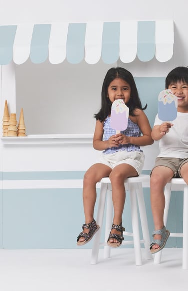 Fashion campaign photography - two children sitting on stools in front of a ice cream shop