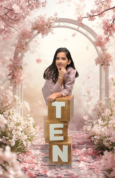 Young girl celebrating her 10th birthday in a studio with pink cherry blossoms and wooden letter blocks.