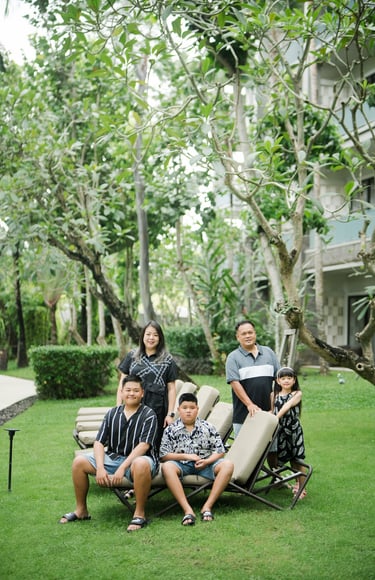 family photography at Movenpick Jimbaran Bali with parents and children sitting together on a green garden lawn