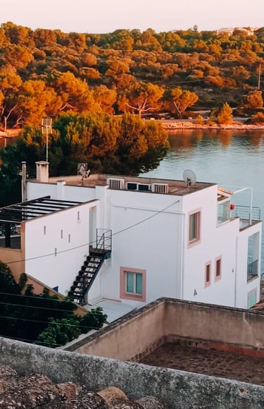 a white house with a staircase leading to a balcony in portocolom