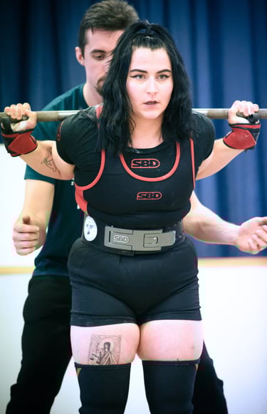 Une jeune femme en singlet pratiquant le squat pour une compétition de powerlifting