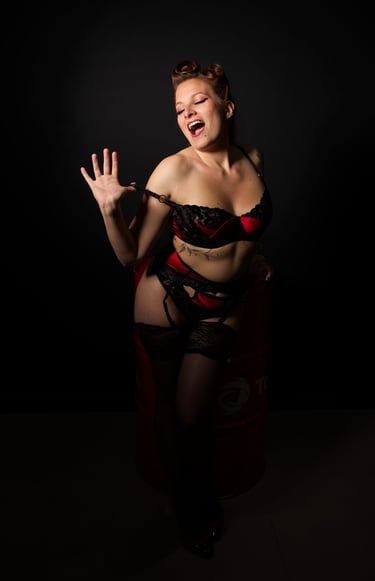 Glamour. Femme en lingerie rouge et noire qui se déshabille en souriant.