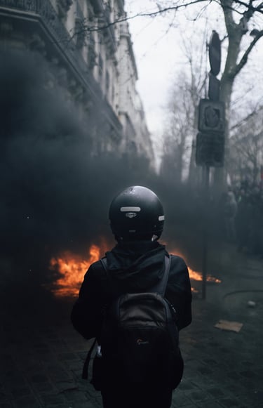 Manifestation contre la réforme des retraites 2023. Un journaliste de dos observe un feu.